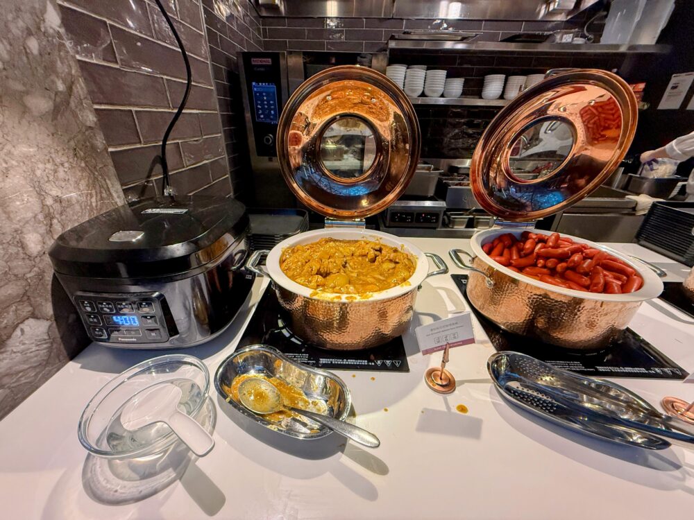 桃園国際空港プライオリティパス対応ラウンジのビュッフェに並ぶカレーとウインナーの温かい料理