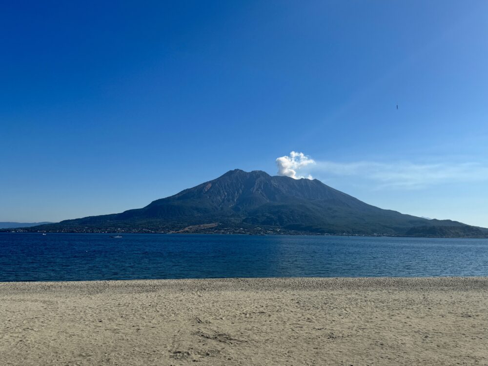 噴煙を上げる桜島と海砂浜