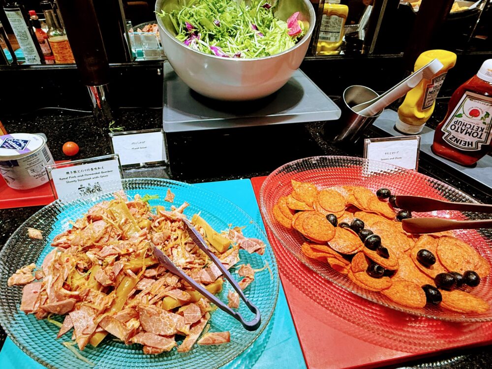 ビュッフェ台に並ぶ冷製料理。焼き豚とメンマの香味和え、サラミ、フレッシュサラダ。
