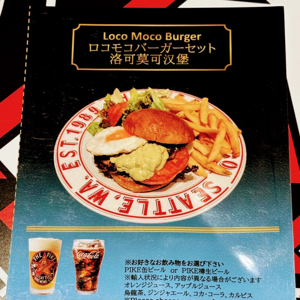 プライオリティパス専用セットメニュー「ロコモコバーガーセット」の案内カード。アボカドソースと目玉焼きをのせたバーガーとフライドポテトが白いプレートに盛られた写真と、選べるドリンク(PIKE缶ビール・樽生ビール・ソフトドリンク各種)の説明が記載されている。
