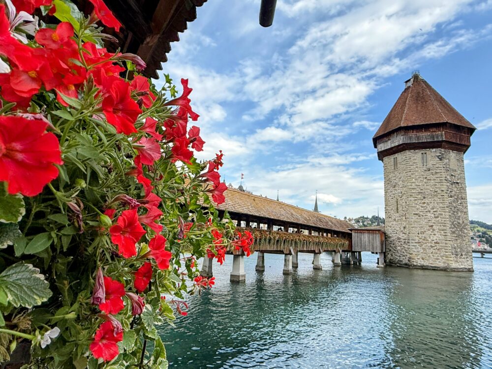 ルツェルン旧市街のシンボル、花で彩られた木造のカペル橋と水の塔。湖に映る姿が美しい人気観光スポット