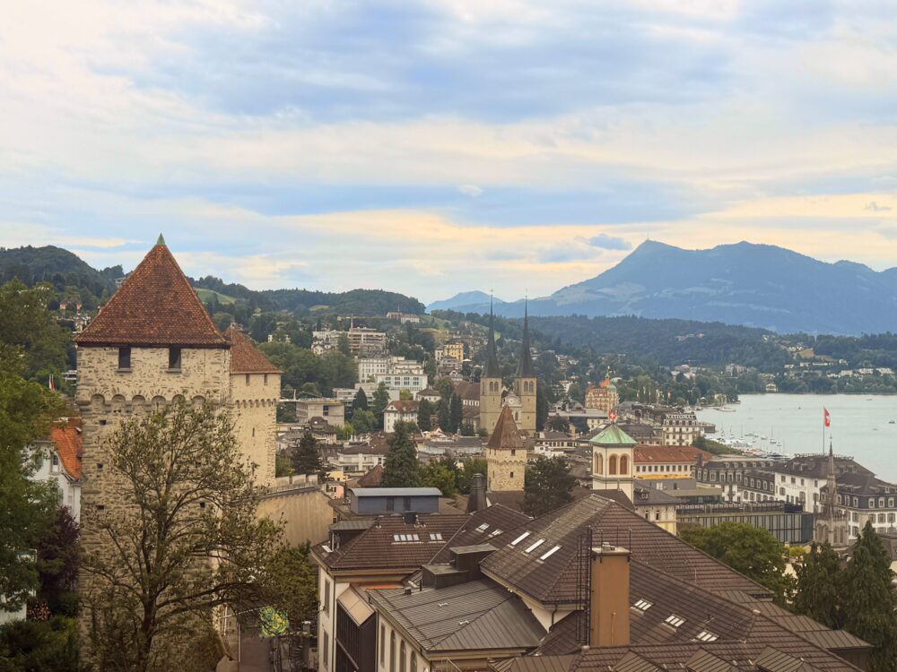 ルツェルン旧市街の城壁『Museggmauer』。赤い屋根の塔と街並みの向こうに湖とアルプスの山々を望む風景