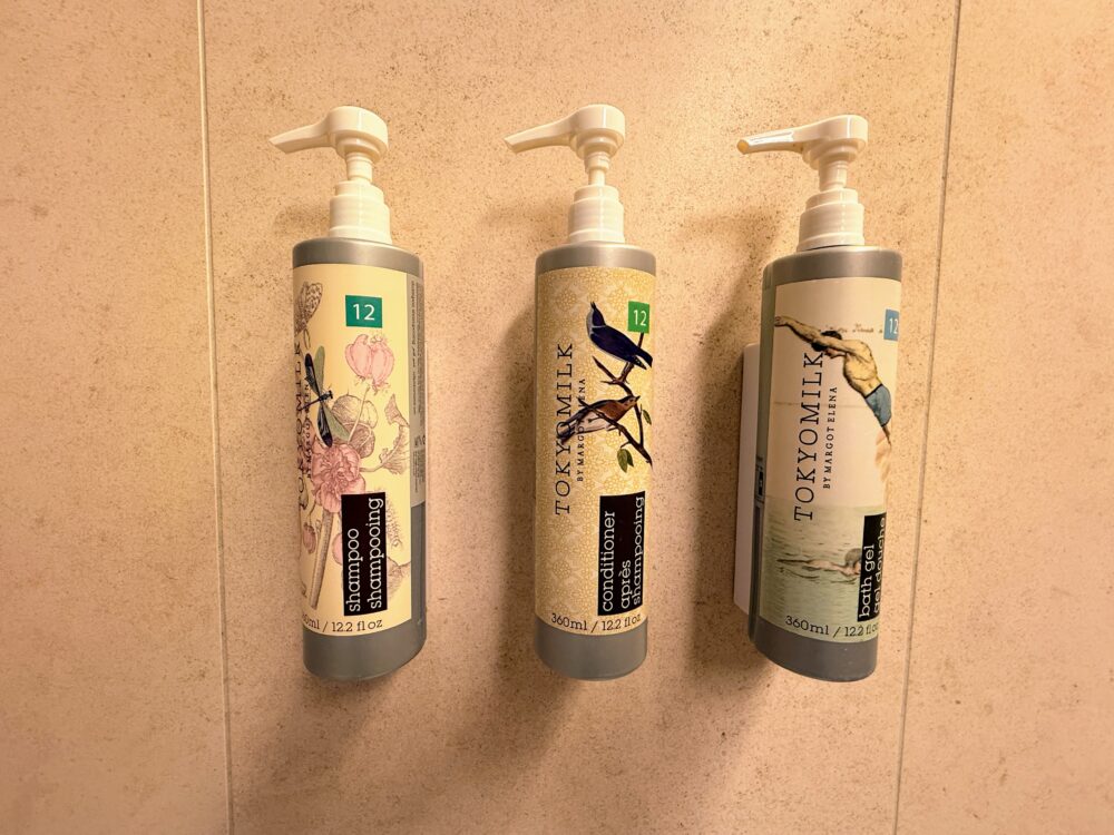 シャワーブースに備え付けられたバスアメニティ。TOKYOMILKブランドのシャンプー、コンディショナー、ボディジェル。
