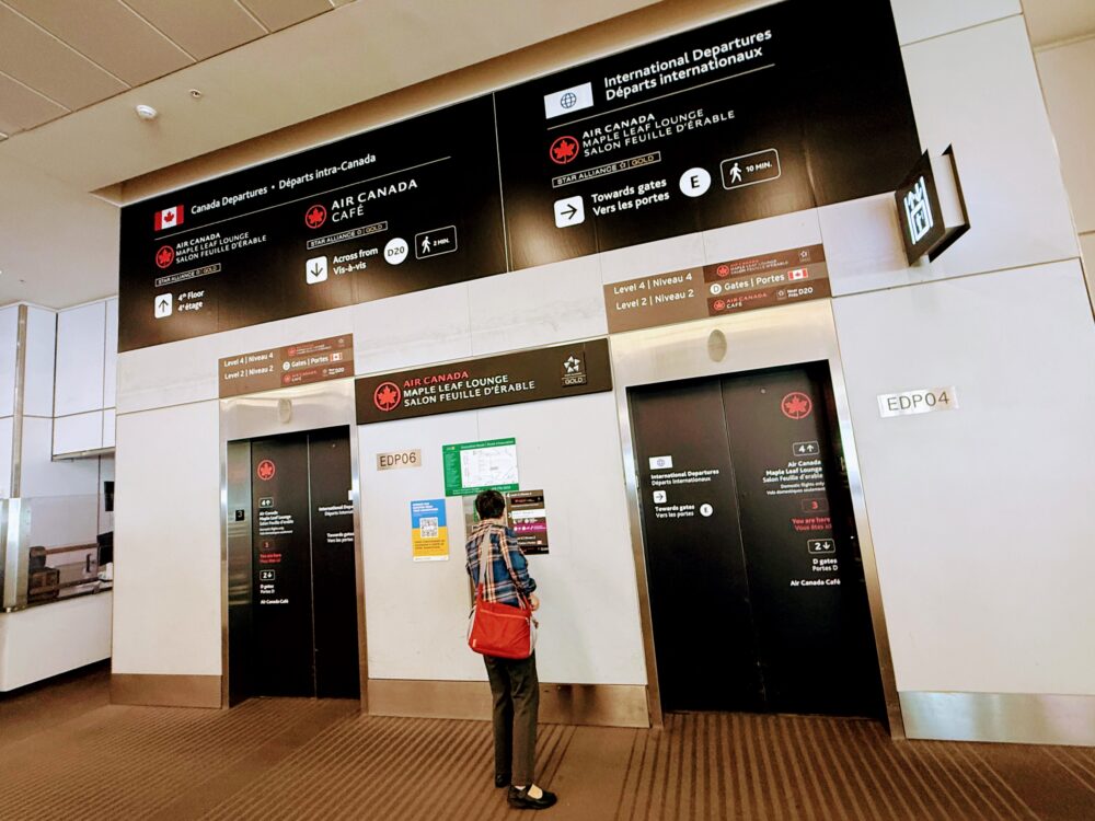 トロント空港第1ターミナルの、メープルリーフ・ラウンジの案内板。国内線と国際線のラウンジの場所を示す看板が写っています。