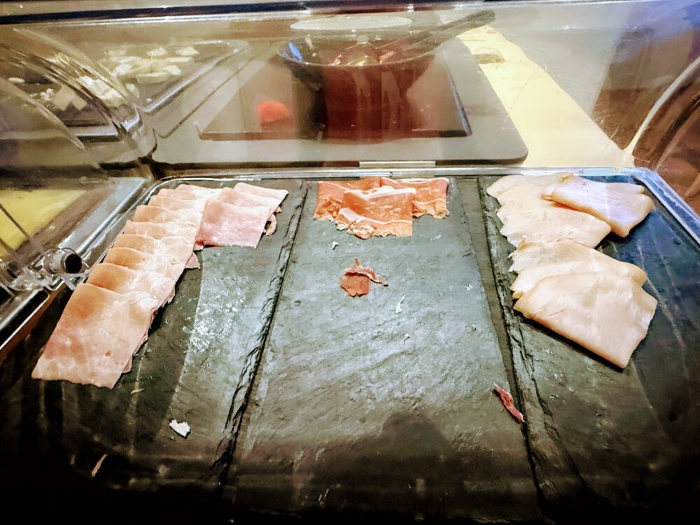 ビュッフェ台に並ぶハムと生ハムのスライス。新鮮で種類豊富なコールドミート。