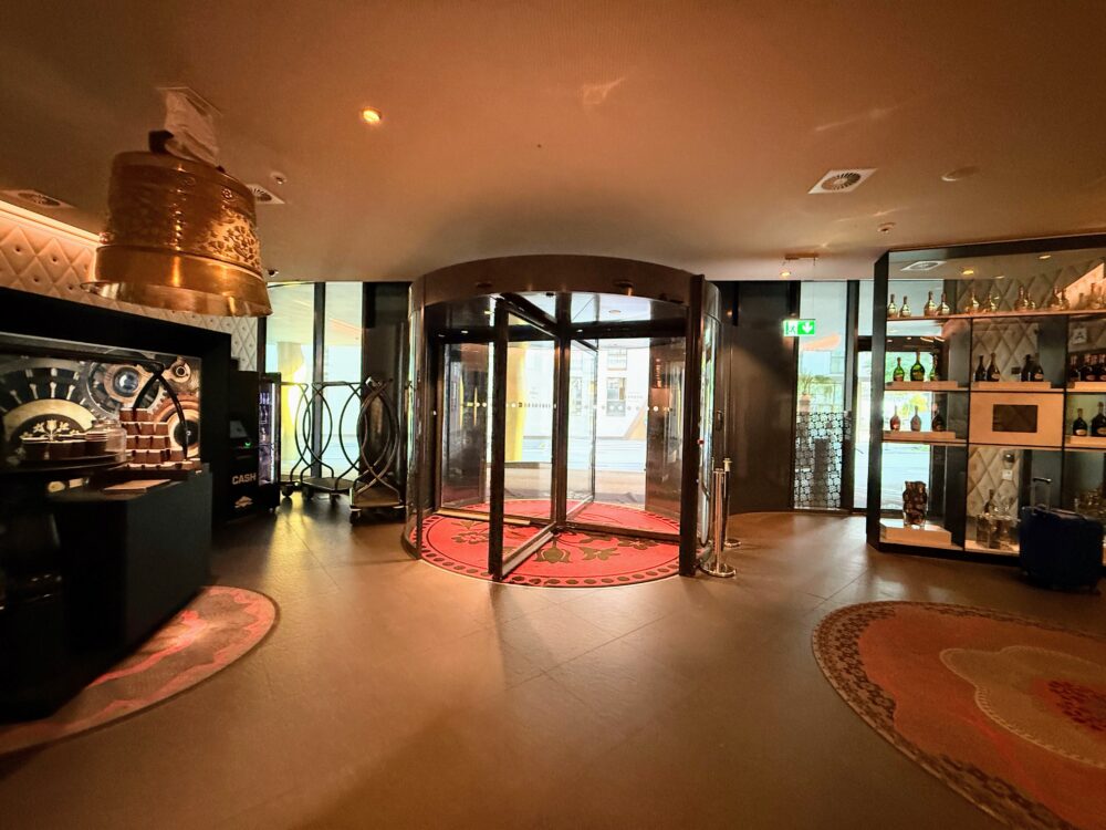 カメハ グランド チューリッヒのエントランスにある回転ドア。天井からスイスのベルを模した装飾が吊り下がっている。