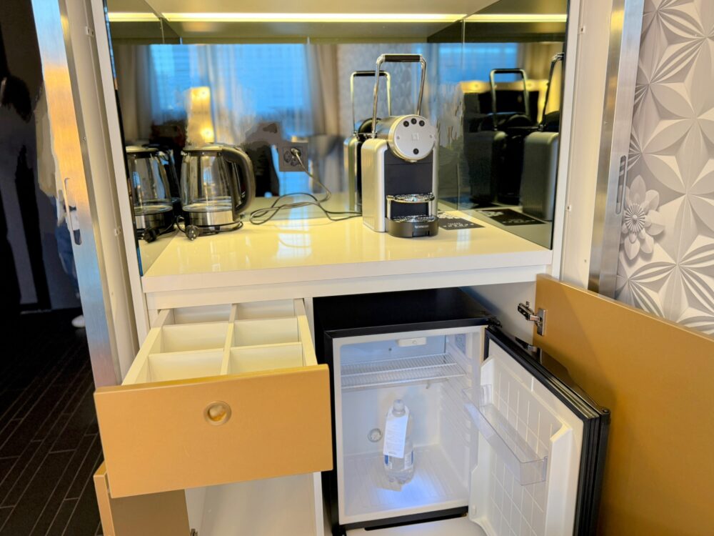 コーヒー/ティーメーカーが置かれたミニバーエリア。ネスプレッソのようなマシン、電気ケトル、冷蔵庫が見える。
