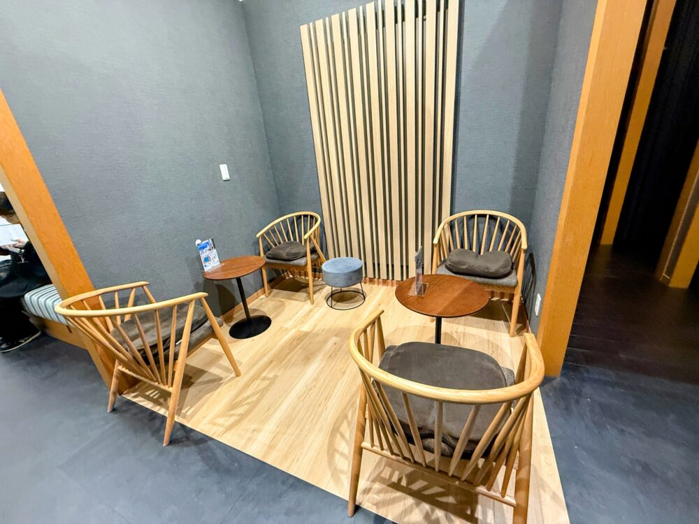 店内の待合スペースの様子。木のデザインチェアと丸いテーブルが配置され、落ち着いた色合いで統一されている。