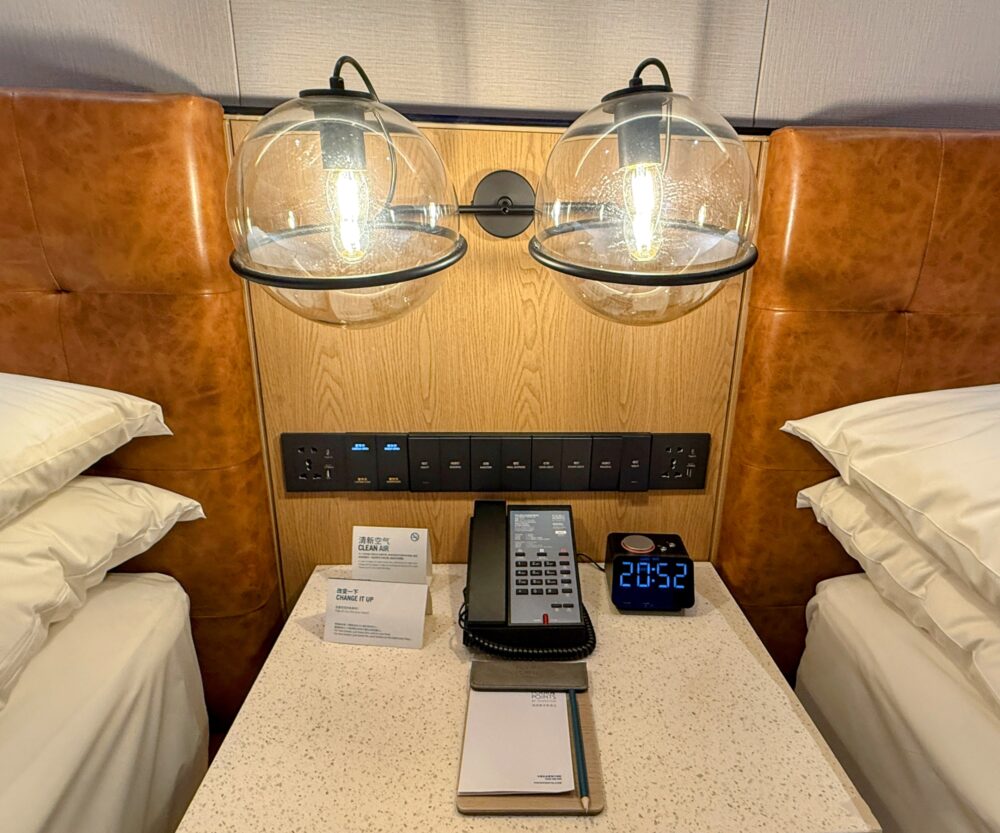 ベッド間のナイトテーブルと照明。ユニバーサルコンセント、USBポート、時計、電話が整い、機能的な設計。