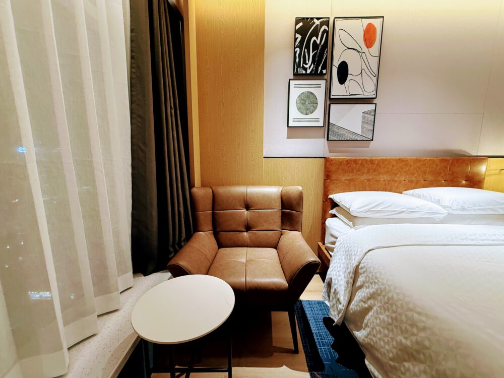 客室窓際のソファと円形テーブル。レザー調の椅子が配置され、読書やティータイムにも最適なくつろぎスペース。