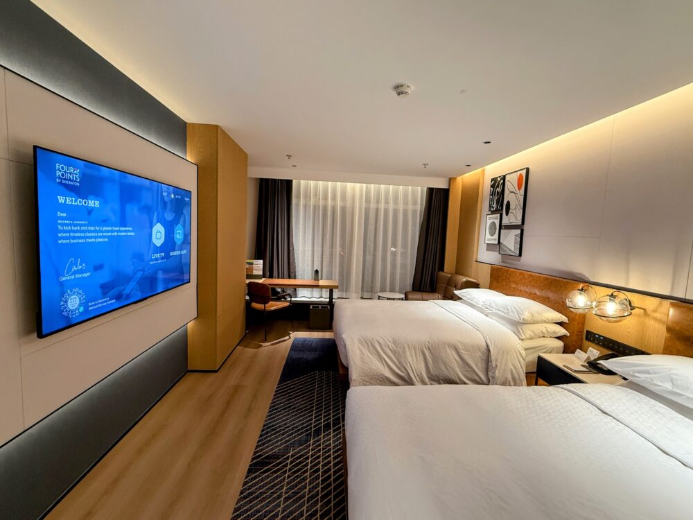 フォーポイント バイ シェラトン 北京三里屯ワーカーズスタジアムのツインルーム全景。39㎡の広々とした空間にベッド2台とデスク、ソファが配置されたスタイリッシュな客室。