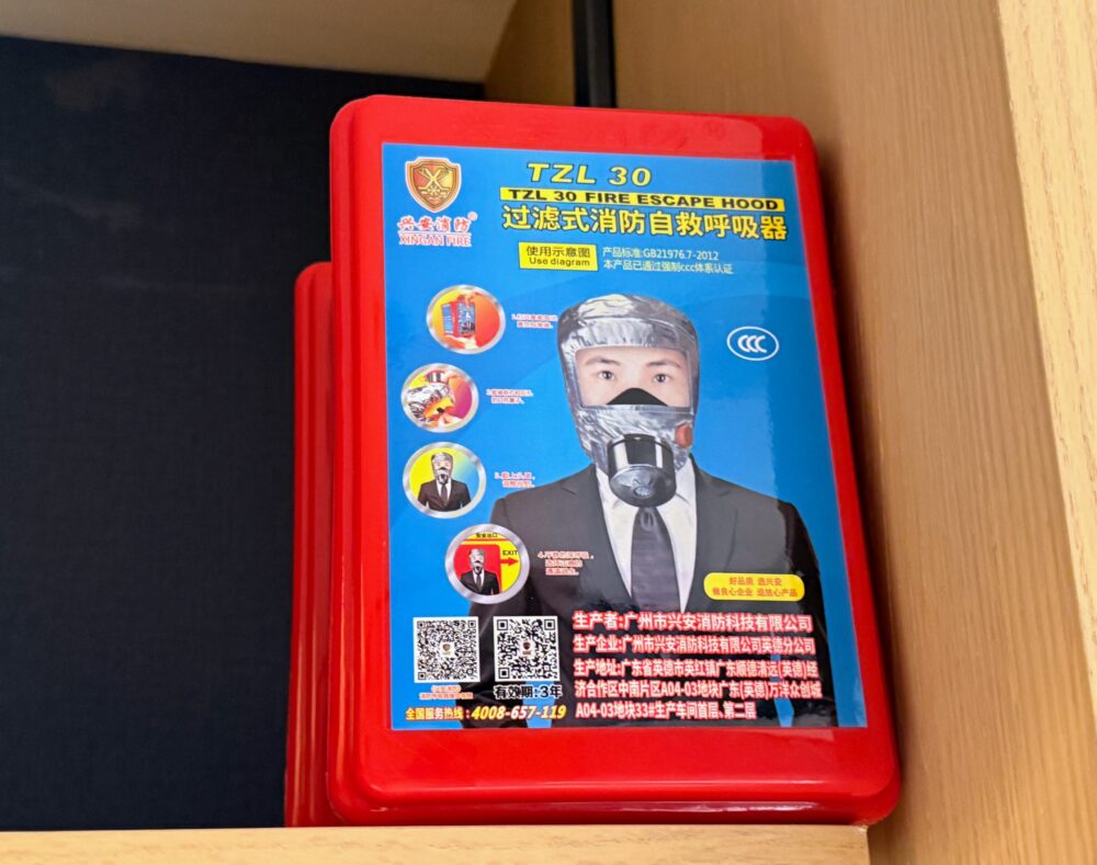 クローゼット内に備え付けられた赤いケース入りの防煙・防火用緊急脱出マスク（Escape Hood）。火災時に使用する非常用安全装備。