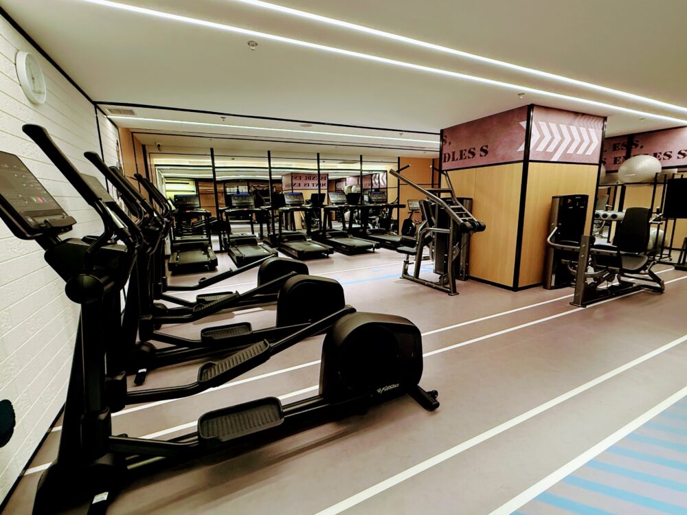 清潔感あるフィットネスジム。ランニングマシンやトレーニングマシンが並ぶ。