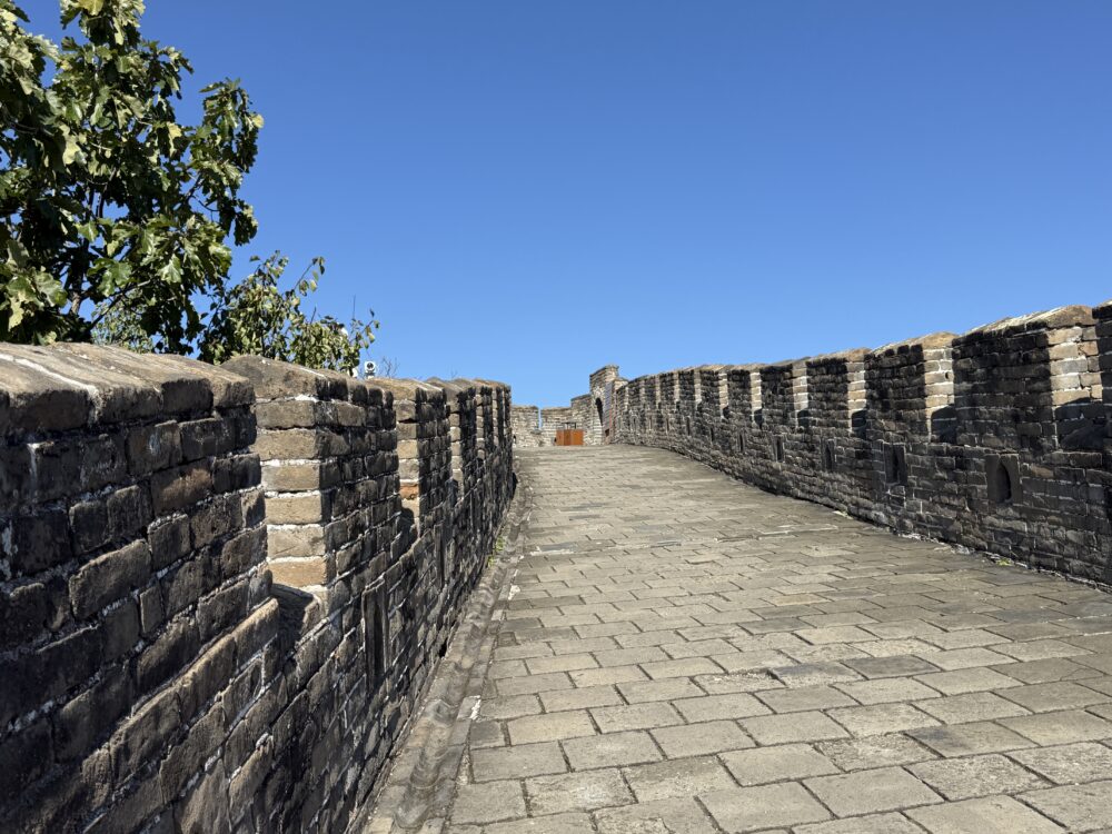 慕田峪長城の誰もいない石畳の通路。青空の下で続く静かな城壁が印象的。