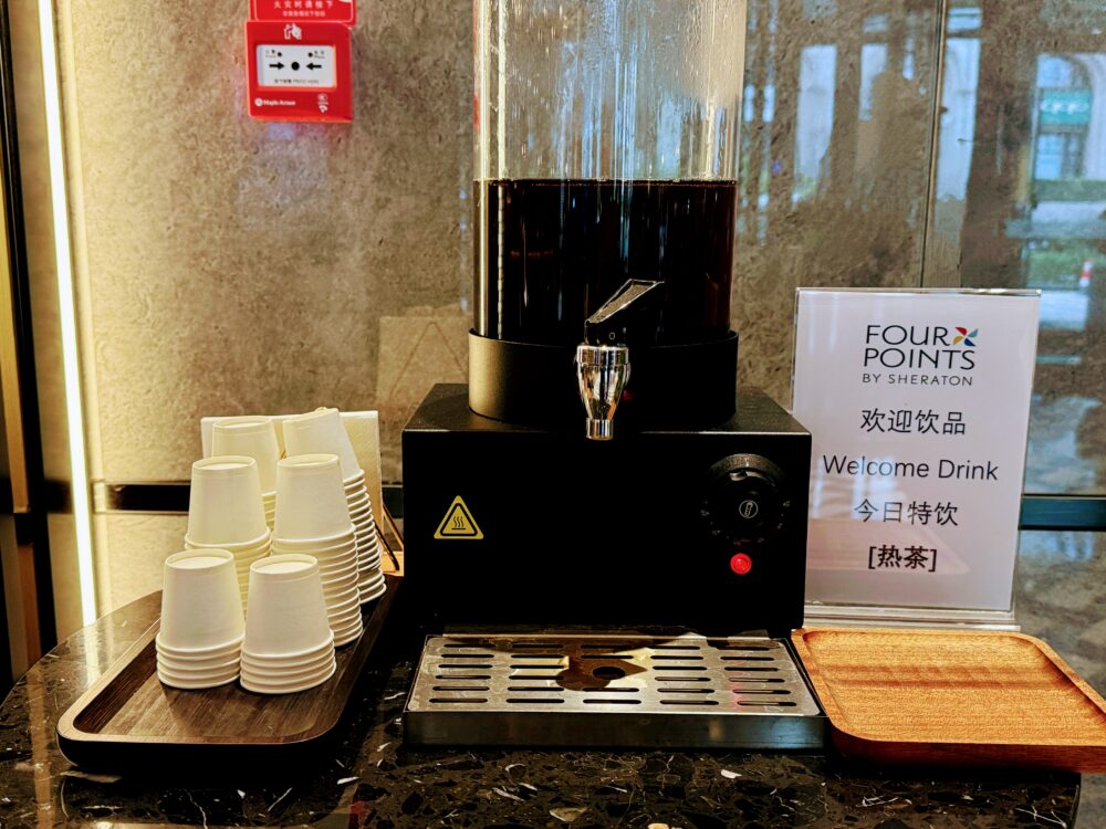 フォーポイント バイ シェラトン 北京三里屯ワーカーズスタジアムのロビーに設置されたウェルカムドリンクコーナー。紙コップとともに温かい紅茶が自由に楽しめる。