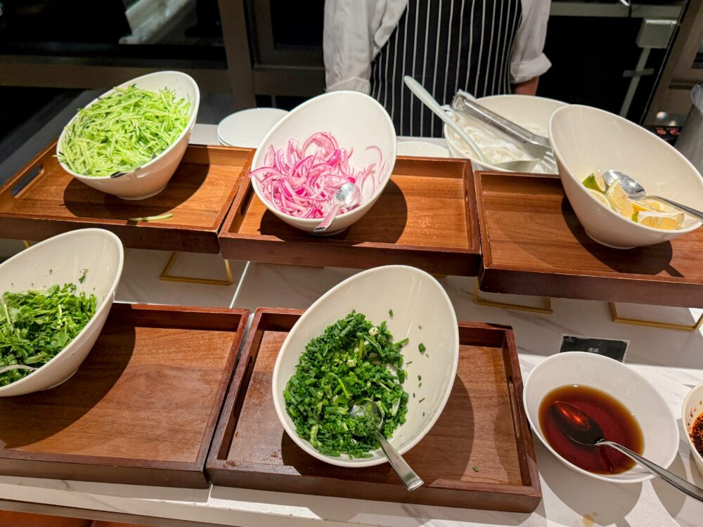 ネギ、香草、赤玉ねぎ、ライム、タレ類が並ぶ