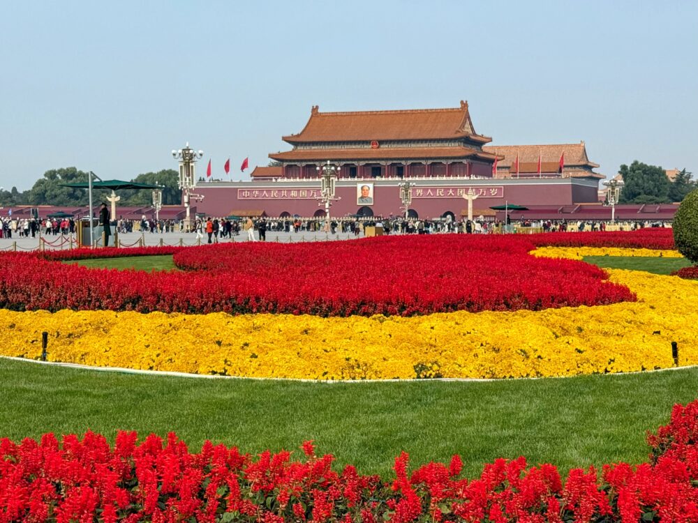 天安門広場の花壇越しに見える天安門。赤と黄色の花が鮮やかに植えられている。