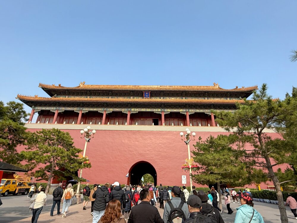 紫禁城の正門・午門を正面から見た写真。赤い城壁と金色の屋根が重厚で、多くの観光客が門へ向かって歩いている様子。