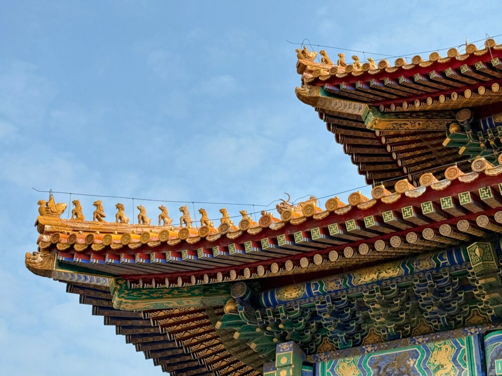 太和殿の屋根の端を近距離で撮影した写真。金色の屋根飾りや並んだ神獣、赤と青の極彩色の装飾が見え、紫禁城の宮廷建築の精巧さが伝わる。