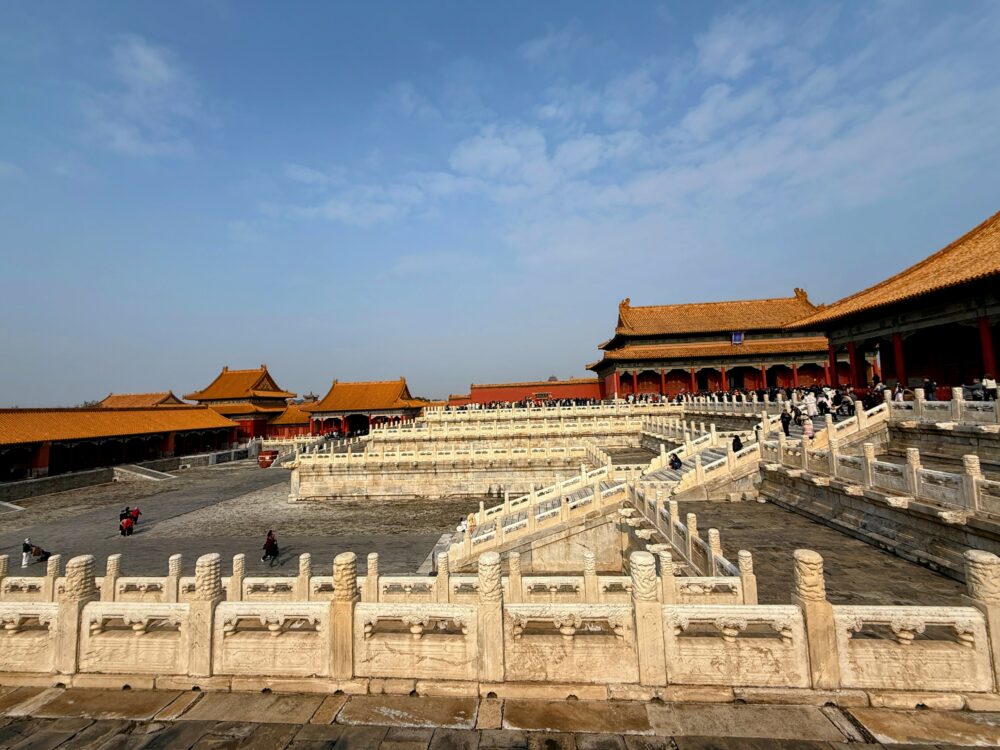 中和殿へ続く高台の回廊と大理石の欄干を広角で撮影した写真。奥には金色の屋根を持つ中和殿が見え、多くの観光客が行き交っている。
