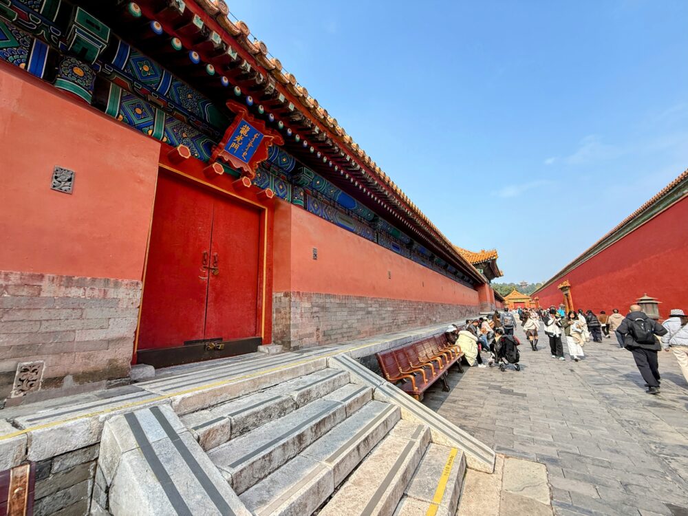 故宮の保和殿北側に続く赤壁の回廊。右側にベンチが並び、多くの観光客が次の宮殿へ向かって歩いている