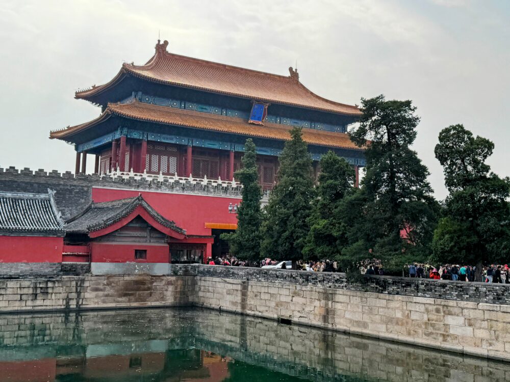 故宮北側の神武門とその前に広がるお堀を撮影した写真。赤い外壁と青い屋根が印象的に写っている。