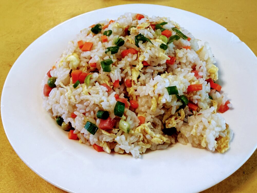 人参・ネギ・卵が入ったシンプルなチャーハンが白い皿に盛られている。