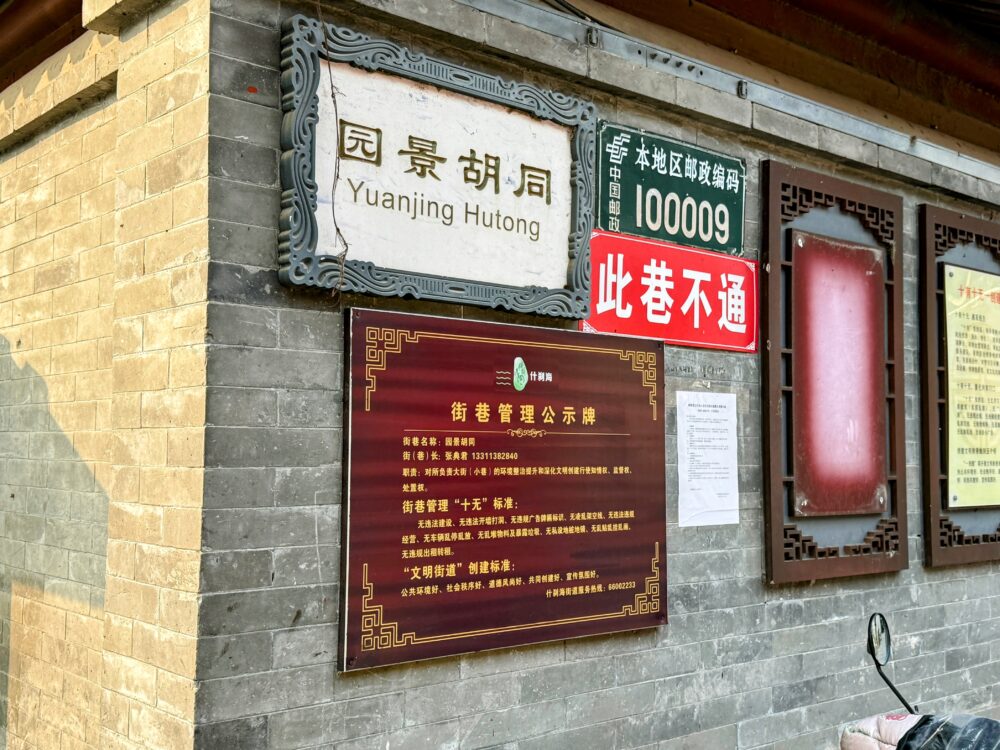 園景胡同（Yuanjing Hutong）の入口にある看板と案内板が並ぶ壁の様子