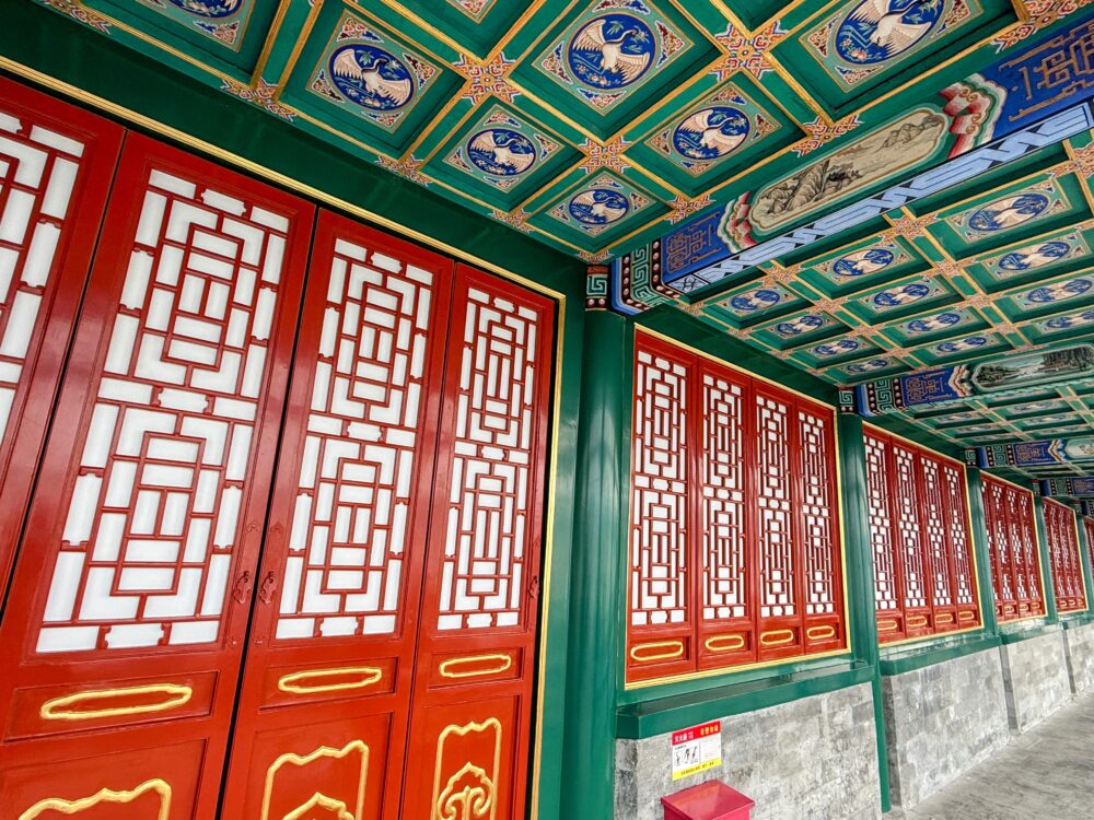 赤い格子窓が並ぶ伝統的な建築と、青・金・緑の色彩豊かな装飾天井が美しい北海公園の回廊。