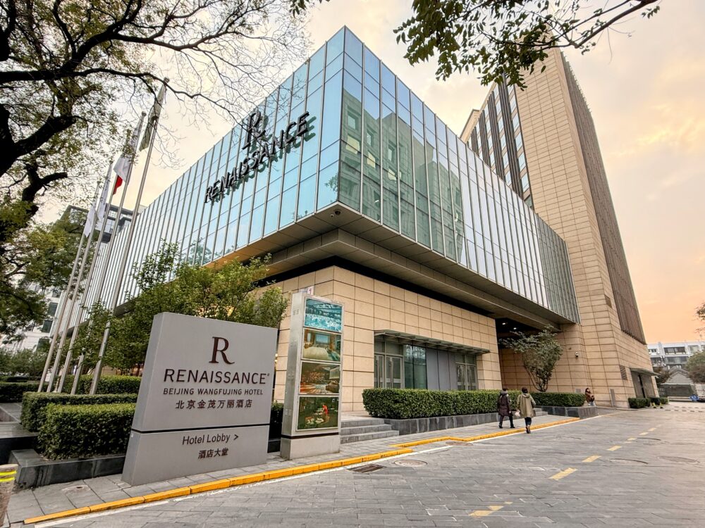 ルネッサンス北京王府井ホテルの外観。ガラス張りのモダンな建物で、エントランス前にはホテル名と「北京金茂万丽酒店」と書かれたサインが立つ。王府井大街の中心に位置する高級ホテル。