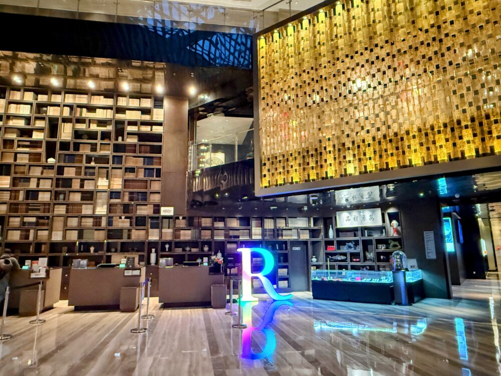 ルネッサンス北京王府井ホテルのロビー。天井まで届く本棚風のデザインウォールと金色のアート照明が印象的なチェックインカウンター。