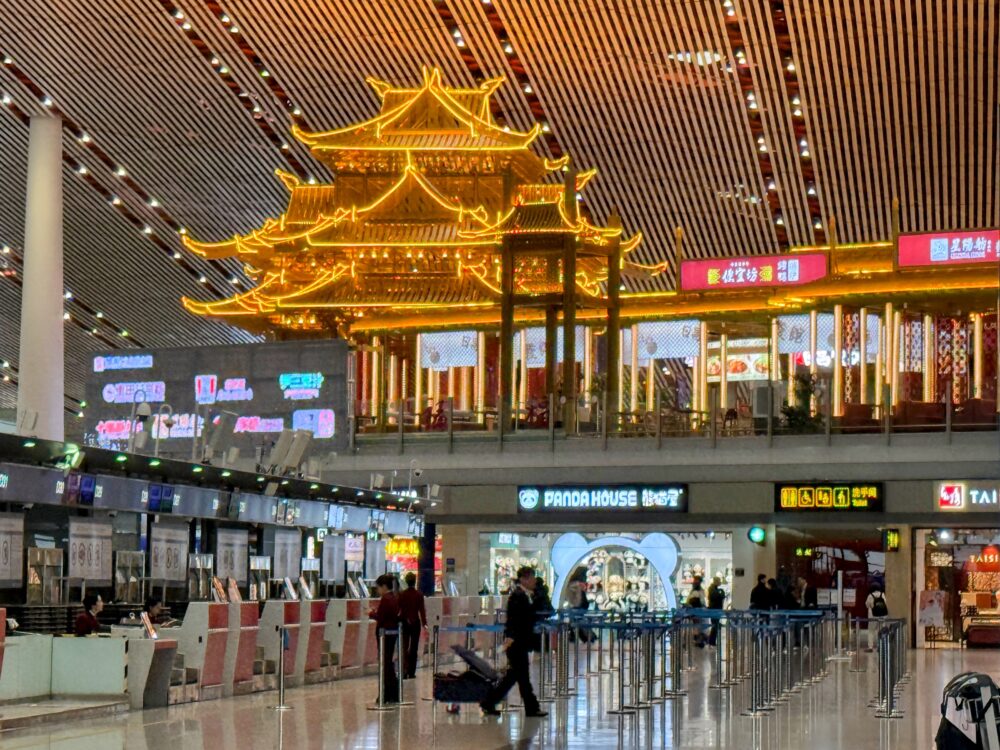 北京首都国際空港ターミナル内の出発ロビー。中国らしい金色の装飾が施された伝統建築風のレストランがあり、モダンな空港建築と融合した華やかな雰囲気が印象的。