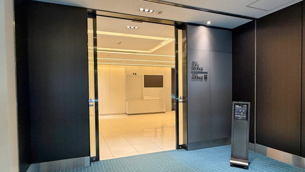 羽田空港国内線ANAスイートラウンジとANAラウンジ共通のエントランス。黒とシルバーを基調とした高級感ある自動ドアの奥に、明るく上品な受付エリアが見える。
