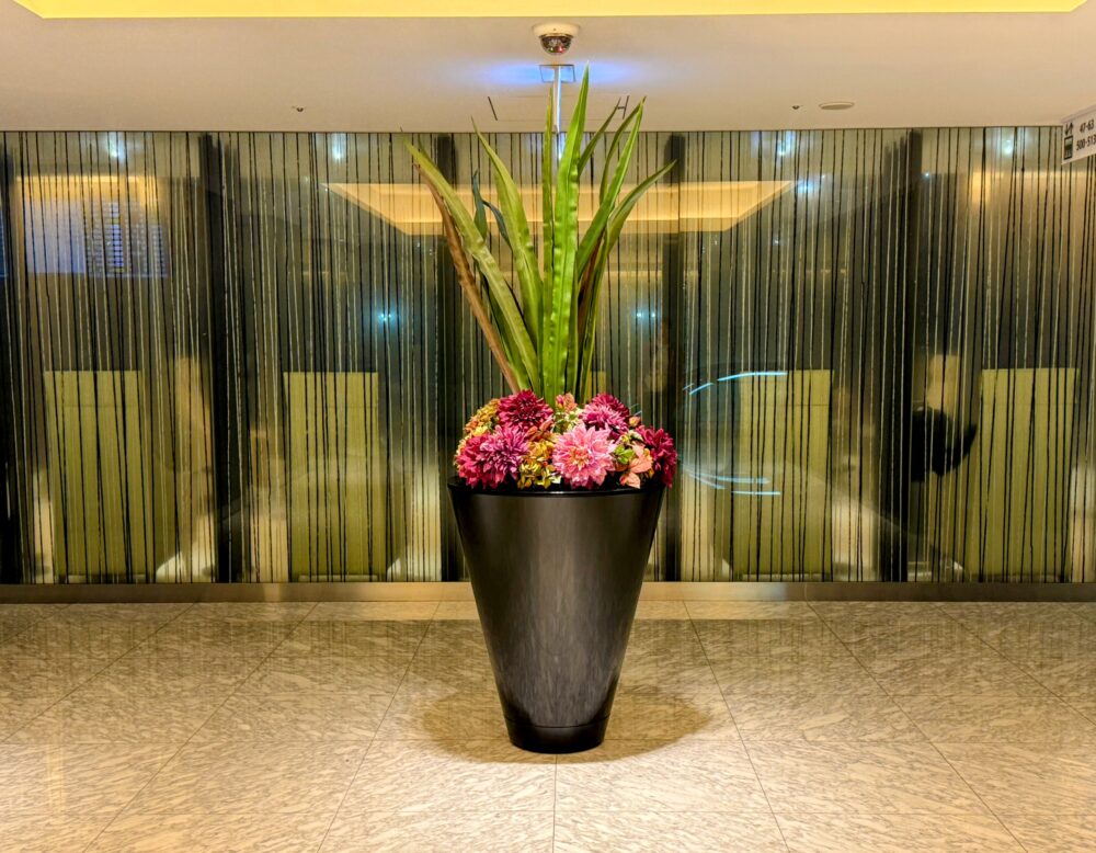 羽田空港国内線ANAスイートラウンジ入口に飾られた大型フラワーアレンジメント。落ち着いた照明とガラス壁が上質な雰囲気を演出している。