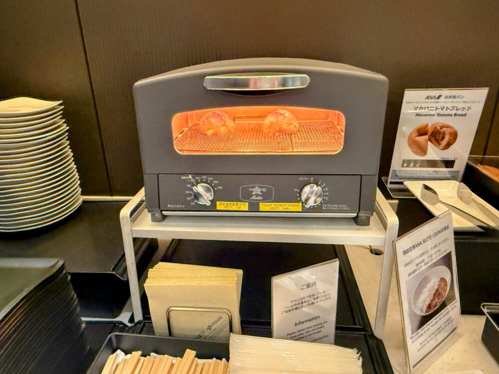 羽田空港ANAスイートラウンジのパンコーナーに設置されたトースター。人気の「マカロニトマトブレッド」を温められるほか、ANA特製カレーと一緒に楽しめるよう案内が掲示されている。