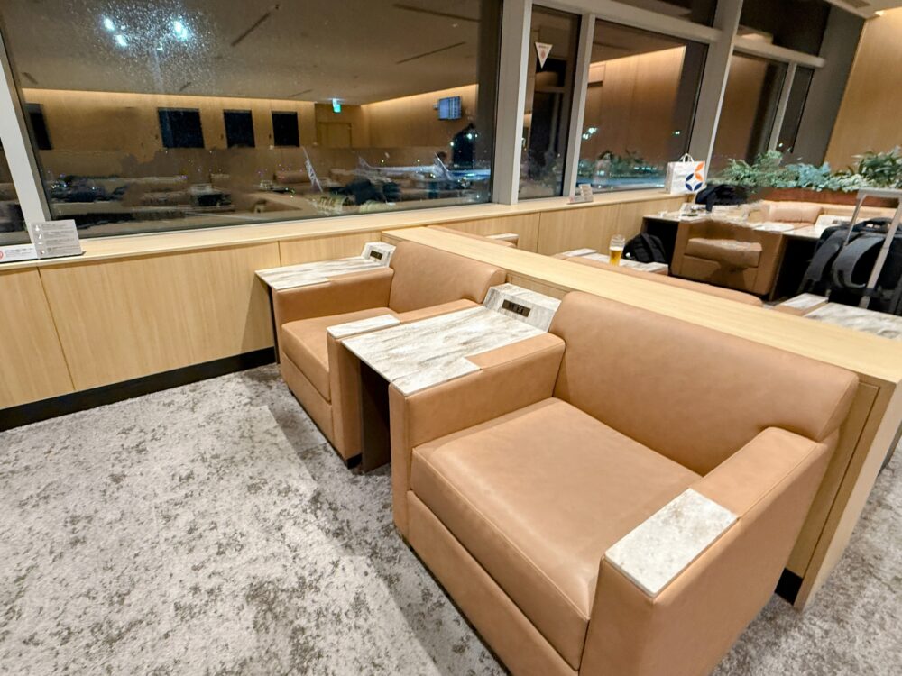 窓際のペアソファ席。広々とした座面とテーブルがあり、飛行機を眺めながらゆったり過ごせるエリア。