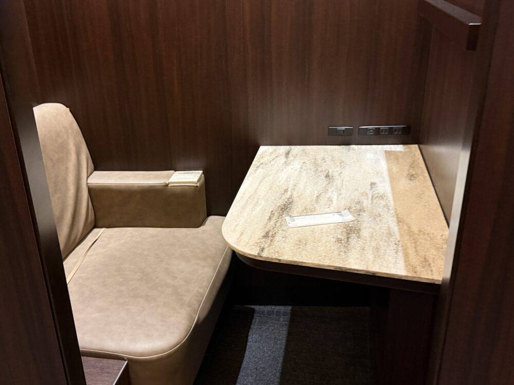 個室タイプのワークブース。レザーシートと木目調デスクが配置され、電源コンセントも完備。