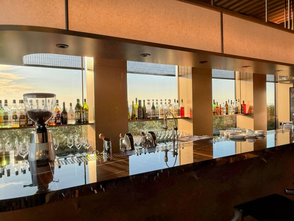 リッツ・カールトン福岡 クラブラウンジのバーカウンターと窓の外に広がる夕暮れの景色