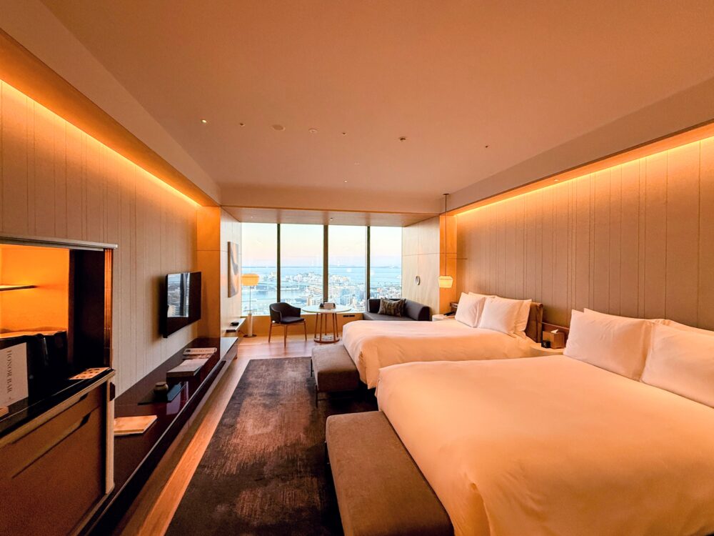 リッツ・カールトン福岡の客室全体。ツインベッドと、大きな窓から博多湾の景色が見える開放的な空間。