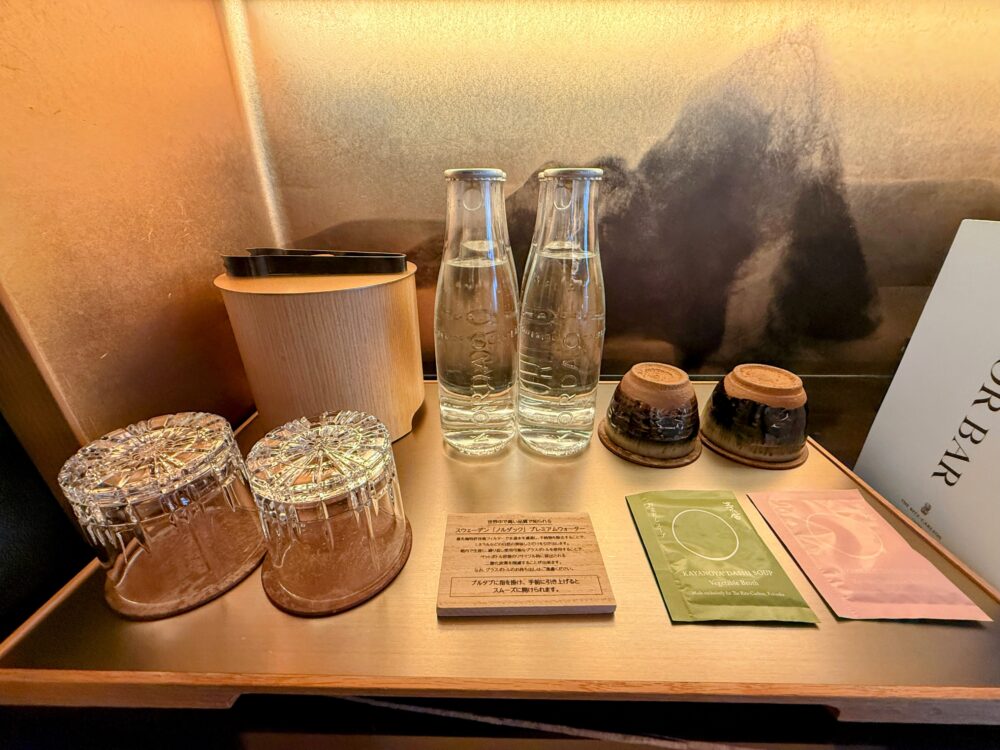 無料で提供されるスウェーデンの「ノルダック」プレミアムウォーターのボトルと、博多・茅乃舎の野菜だしスープ