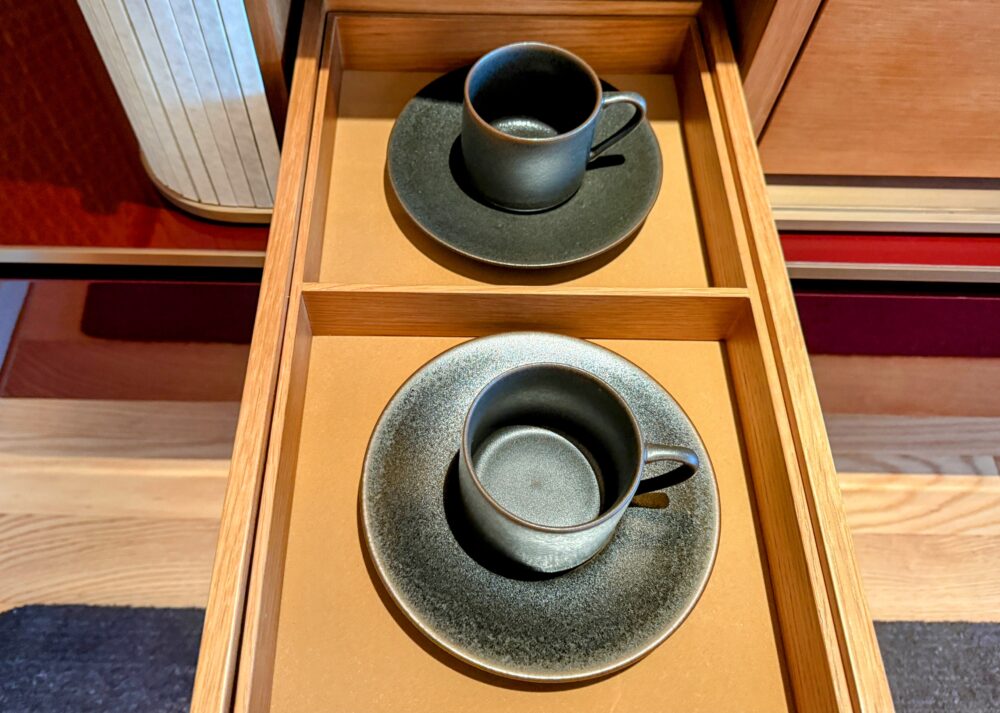 引き出しに収納された、黒を基調としたモダンな陶器のコーヒーカップとソーサー