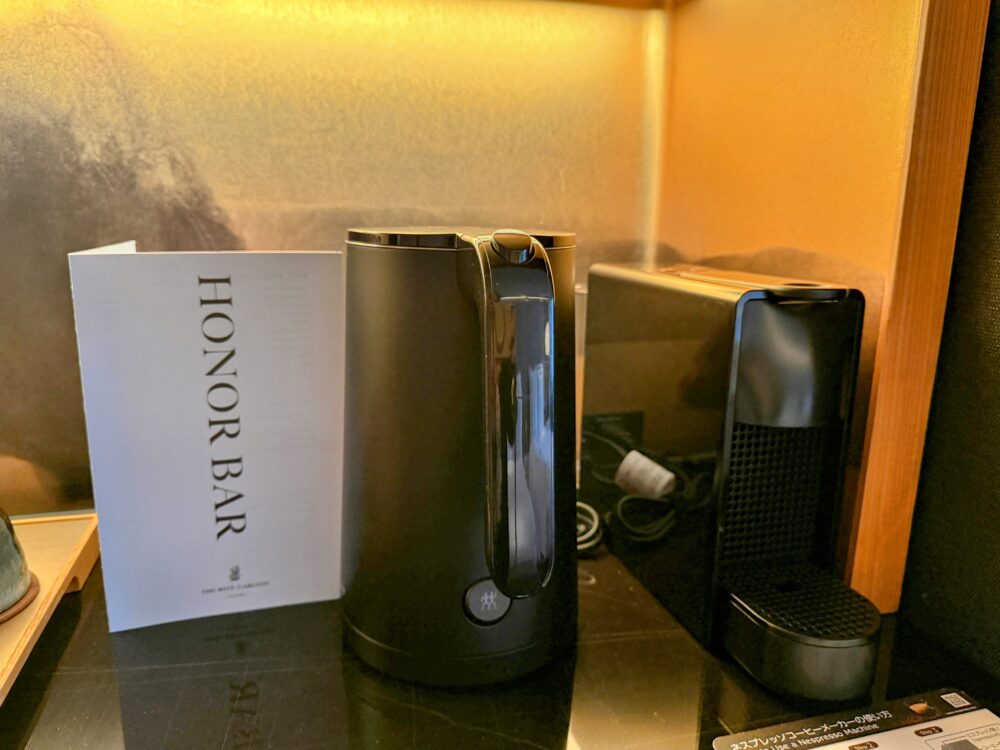 キャビネット内に設置された黒い電気ケトルとネスプレッソコーヒーマシン