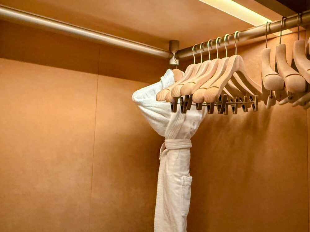 広々としたウォークインクローゼット。たくさんの木製ハンガーと、もう1着のバスローブがかけられている