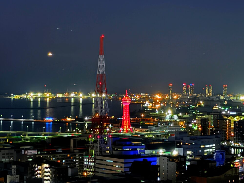 夜闇に赤くライトアップされた博多ポートタワーと、周辺の港湾エリアの幻想的な夜景のアップ。