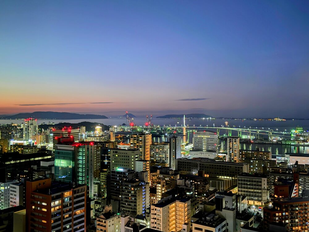 日没後の博多湾のパノラマ夜景。マジックアワーの空の色と、眼下に広がる街の煌めく灯りが美しい。