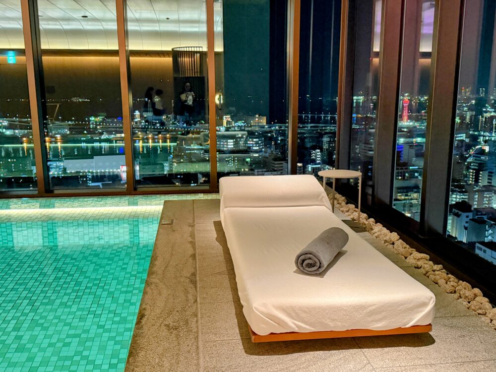 プールサイドの角に設置されたラウンジチェア。2面のガラス窓から福岡の夜景を一望できる特等席。