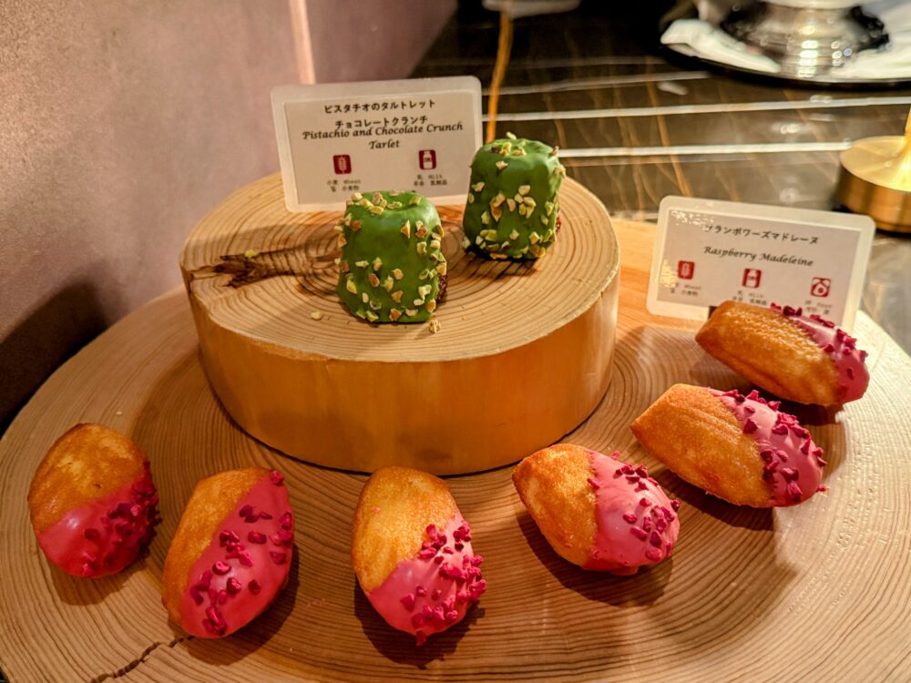 緑色のピスタチオチョコレートクランチタルトと、ピンク色のフランボワーズチョコレートがかかったマドレーヌ。