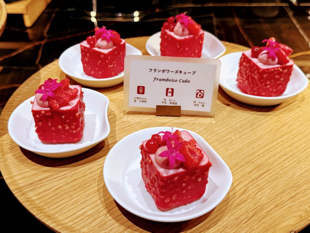 真っ赤なフランボワーズキューブケーキ。上にベリーとエディブルフラワーが飾られている。