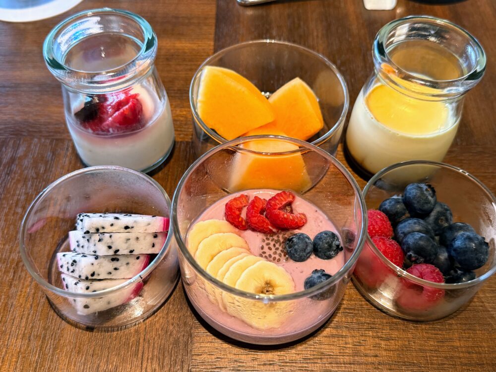 小瓶に入ったヨーグルト・プリンと、カットフルーツ（ドラゴンフルーツ、メロンなど）