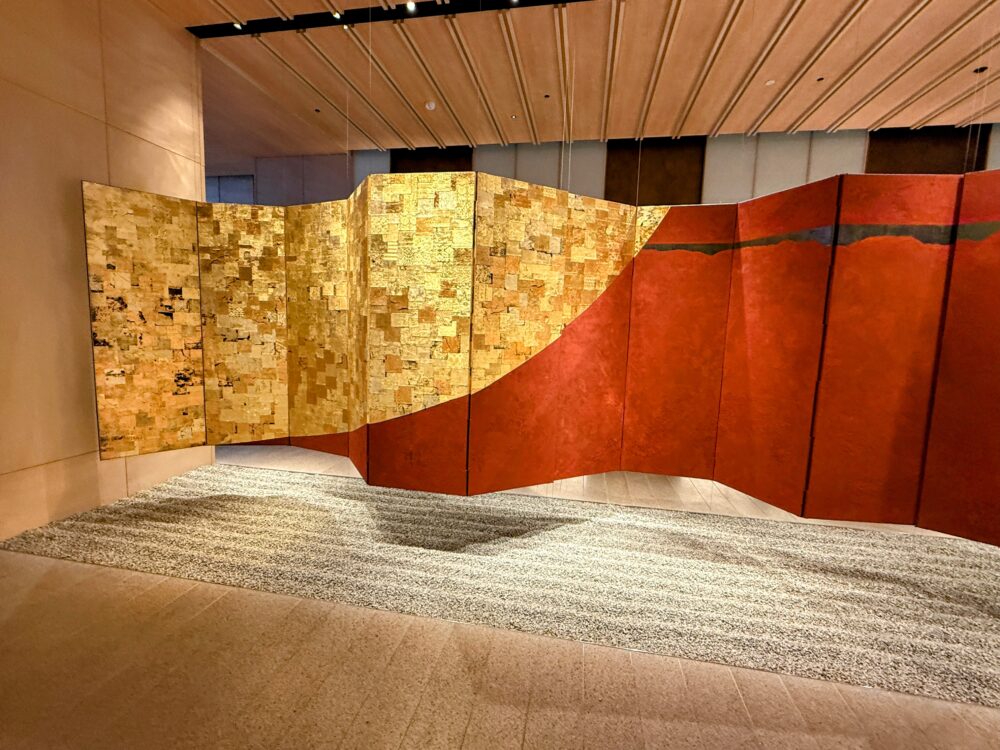 エレベーターホールにある、銀色と黒の帯がデザインされたモダンな屏風